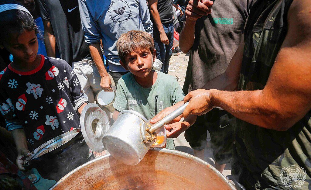 1024px Displaced Palestinians gather to receive food from a charity in Deir el Balah Gaza Strip e1750340144360